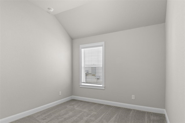 unfurnished room featuring lofted ceiling and carpet flooring