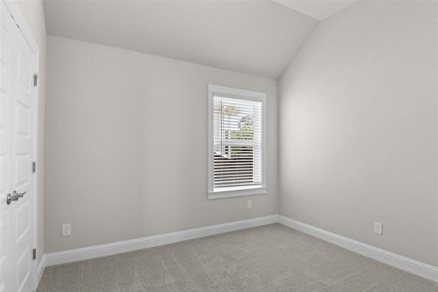 carpeted empty room featuring lofted ceiling