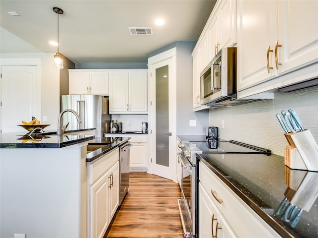 kitchen featuring decorative light fixtures, high end appliances, tasteful backsplash, light hardwood / wood-style flooring, and white cabinets