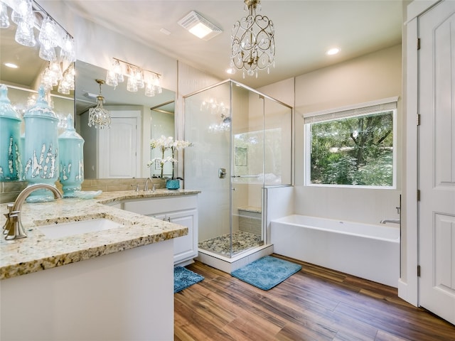 bathroom featuring hardwood / wood-style floors, vanity, plus walk in shower, and a notable chandelier