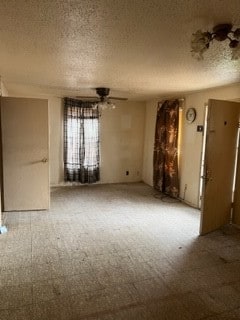 carpeted spare room featuring ceiling fan and a textured ceiling