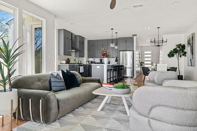 living room featuring light hardwood / wood-style flooring and ceiling fan with notable chandelier