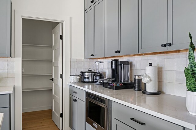 kitchen with light hardwood / wood-style flooring, gray cabinetry, and backsplash