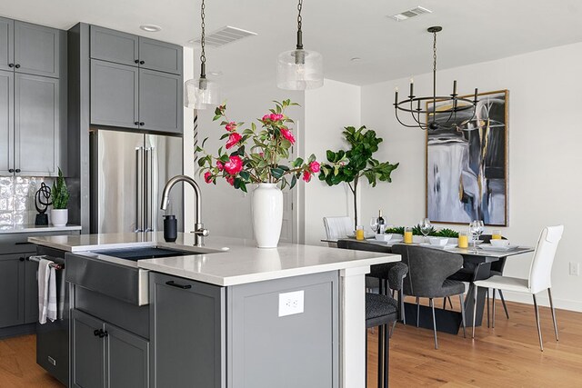 kitchen featuring decorative light fixtures, a chandelier, high quality fridge, and light hardwood / wood-style floors