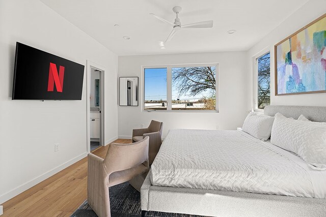 bedroom with ceiling fan, ensuite bath, and hardwood / wood-style flooring