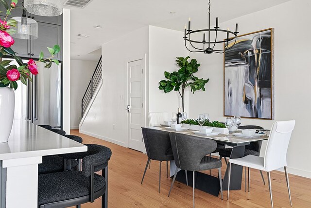 dining area with a notable chandelier and light hardwood / wood-style floors