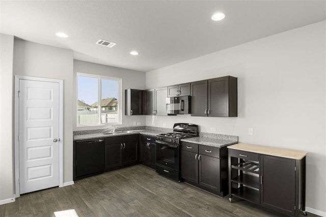 kitchen featuring light stone countertops, dark hardwood / wood-style floors, sink, and black appliances