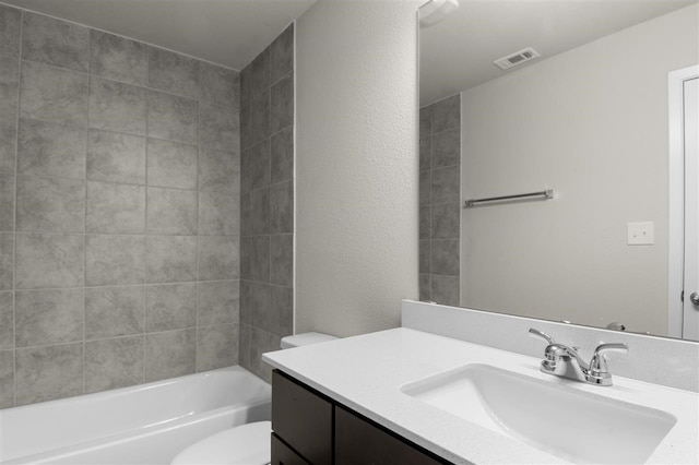 full bathroom with vanity, tiled shower / bath combo, and toilet