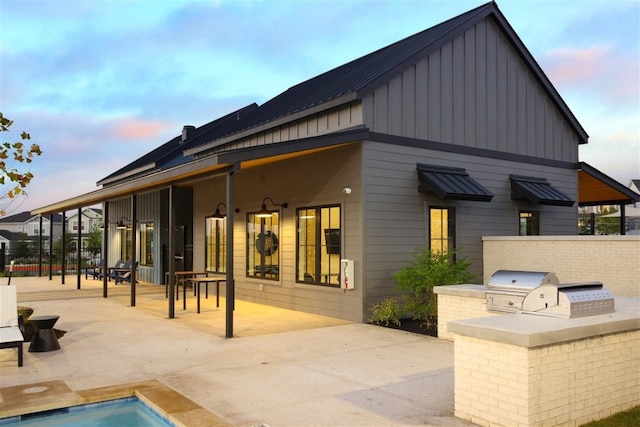 back house at dusk with area for grilling and a patio