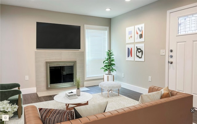 living room with a tiled fireplace, dark wood-type flooring, and plenty of natural light