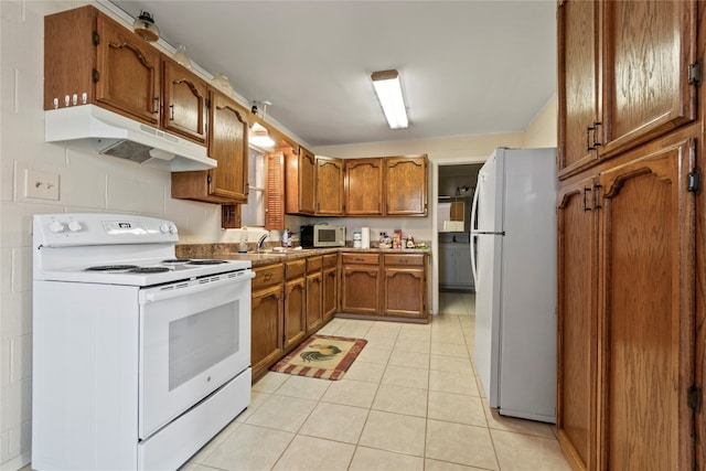 kitchen featuring white appliances, sink, and light tile floors