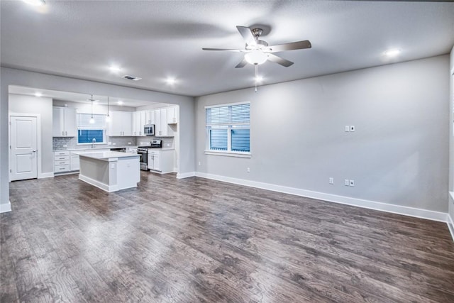 kitchen featuring appliances with stainless steel finishes, white cabinetry, backsplash, hanging light fixtures, and a center island