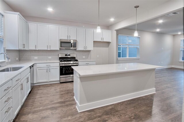 kitchen featuring sink, hanging light fixtures, stainless steel appliances, white cabinets, and dark hardwood / wood-style flooring