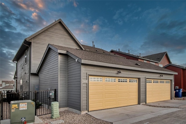 property exterior at dusk with a garage and central AC