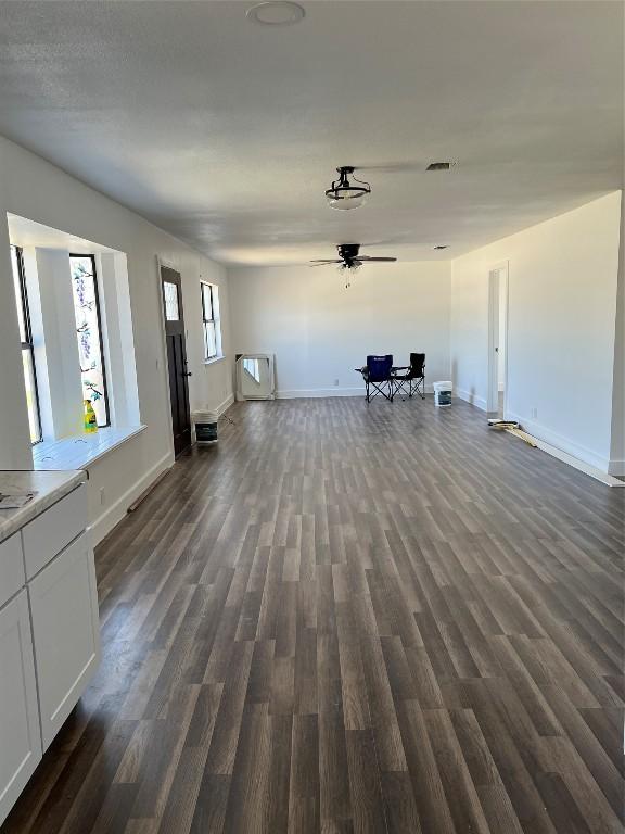 unfurnished living room with dark hardwood / wood-style flooring and ceiling fan