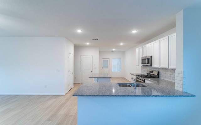 kitchen featuring light hardwood / wood-style floors, appliances with stainless steel finishes, kitchen peninsula, and sink