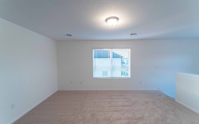 carpeted spare room featuring a textured ceiling