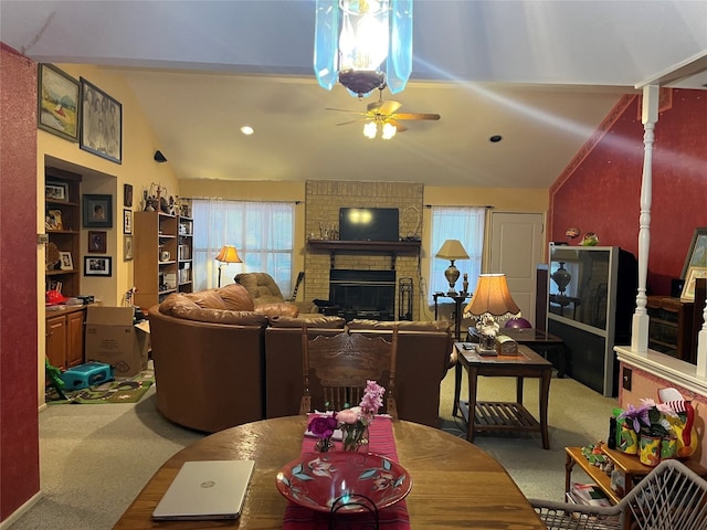 carpeted living room with lofted ceiling, brick wall, ceiling fan, and a brick fireplace