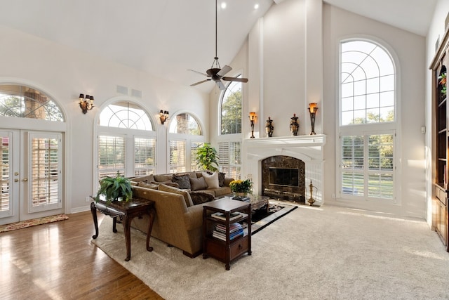 living room with a healthy amount of sunlight, a high end fireplace, ceiling fan, and high vaulted ceiling