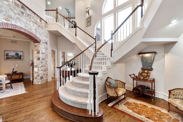 stairs with dark wood-type flooring and a towering ceiling