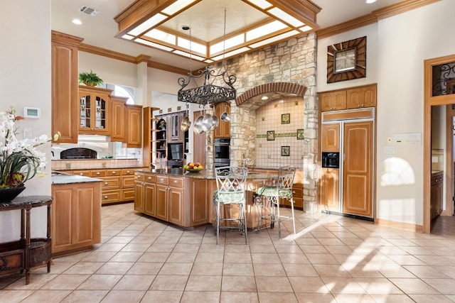 kitchen with a towering ceiling, paneled fridge, light tile floors, and a breakfast bar area