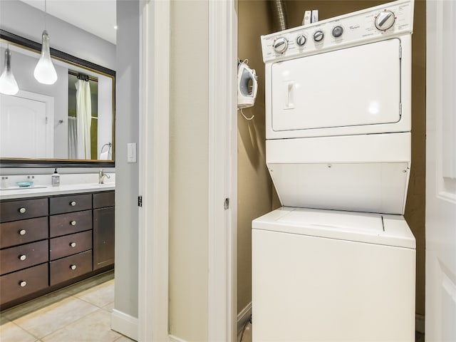 clothes washing area with sink, light tile floors, and stacked washer / dryer