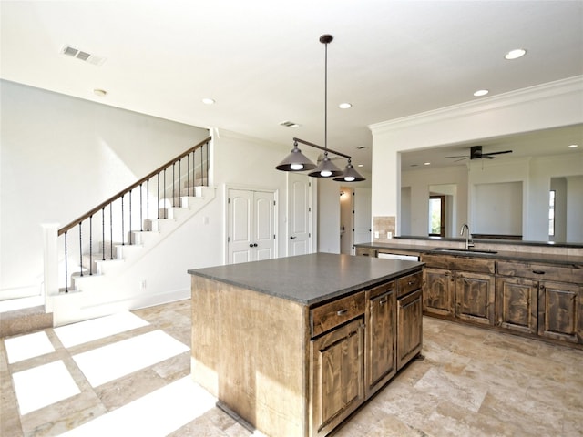 kitchen with ceiling fan, sink, light tile floors, a kitchen island, and ornamental molding