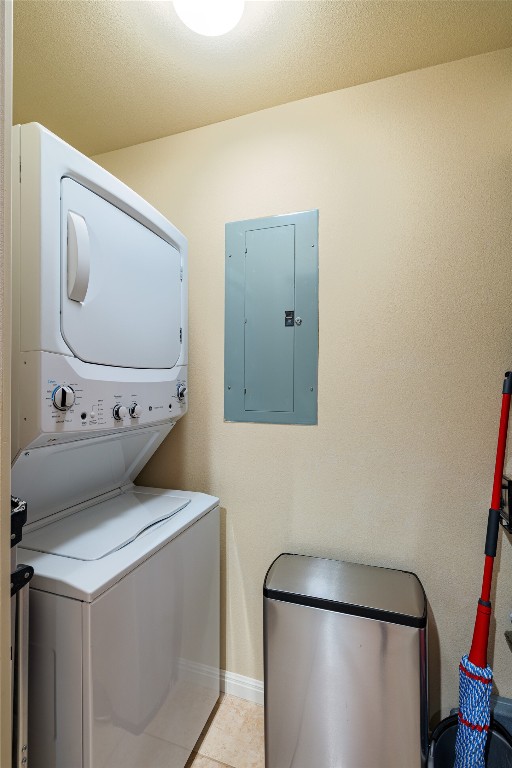 washroom with stacked washer / dryer and light tile floors