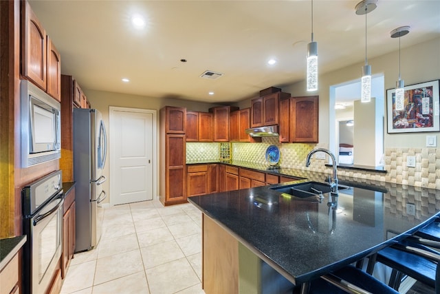 kitchen with hanging light fixtures, stainless steel appliances, kitchen peninsula, backsplash, and sink