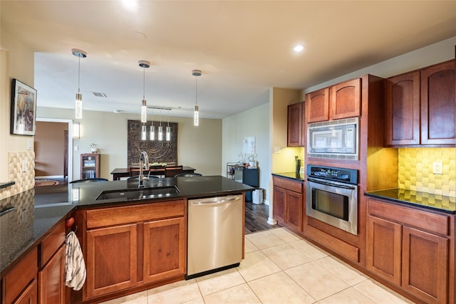 kitchen featuring hanging light fixtures, appliances with stainless steel finishes, sink, and tasteful backsplash