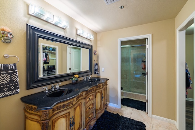 bathroom featuring dual sinks, tile floors, an enclosed shower, large vanity, and a textured ceiling