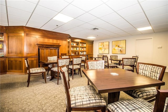 carpeted dining area featuring a paneled ceiling