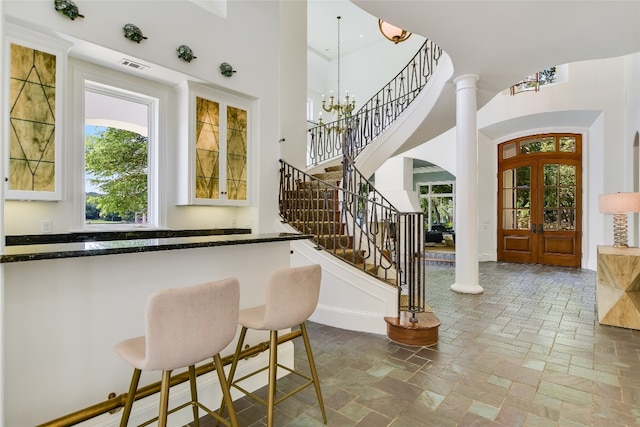 kitchen with decorative columns, french doors, hanging light fixtures, tile floors, and an inviting chandelier