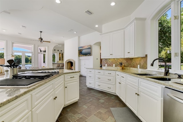 kitchen with backsplash, ceiling fan, a healthy amount of sunlight, dishwasher, and dark tile flooring