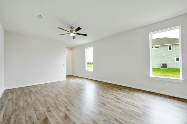 empty room with a wealth of natural light, ceiling fan, and light wood-type flooring