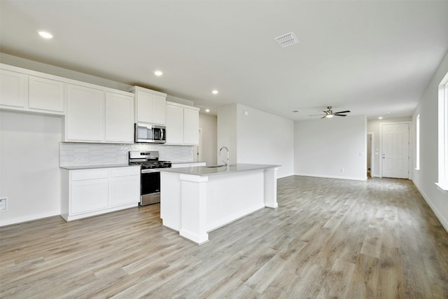 kitchen with appliances with stainless steel finishes, light hardwood / wood-style flooring, and a kitchen island with sink