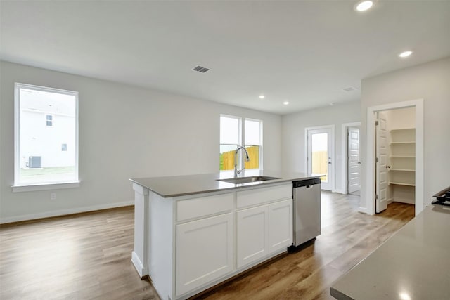 kitchen featuring a healthy amount of sunlight, light hardwood / wood-style flooring, stainless steel dishwasher, sink, and an island with sink