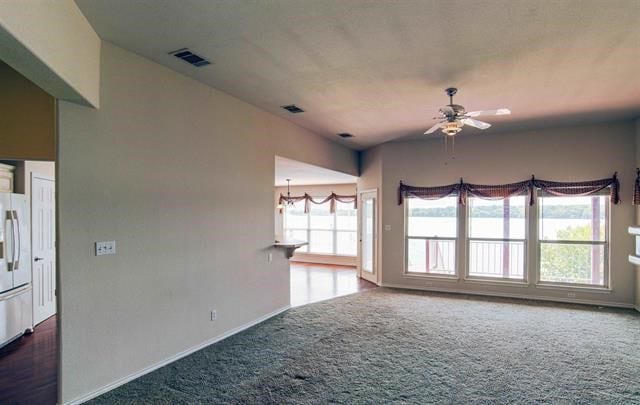 unfurnished room with ceiling fan and dark colored carpet