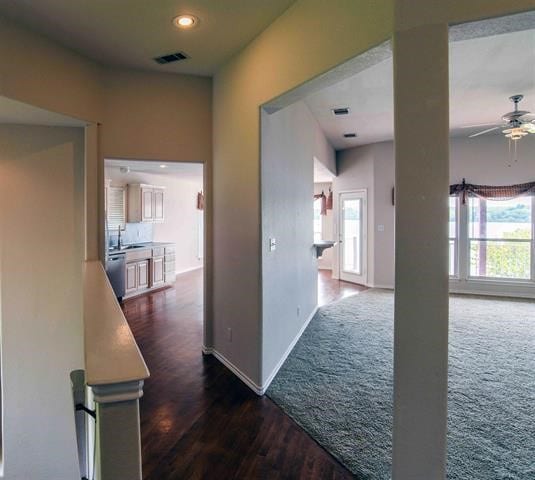 corridor featuring plenty of natural light, sink, and dark colored carpet