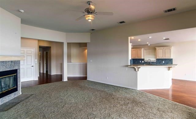 kitchen with kitchen peninsula, ceiling fan, carpet flooring, a premium fireplace, and tasteful backsplash