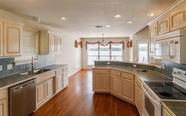 kitchen with white appliances, a wealth of natural light, and dark wood-type flooring