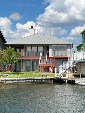 back of house with a water view, a balcony, and a yard