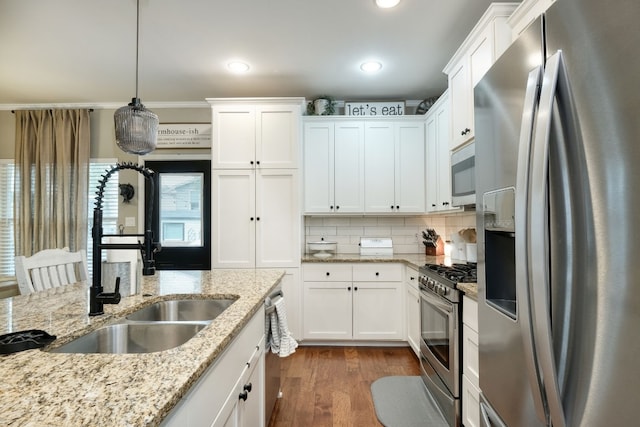 kitchen featuring hardwood / wood-style floors, appliances with stainless steel finishes, white cabinets, tasteful backsplash, and pendant lighting