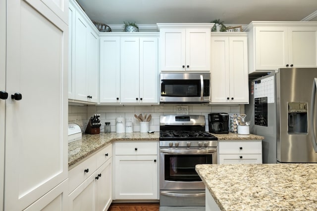 kitchen with white cabinets, tasteful backsplash, light stone counters, and stainless steel appliances