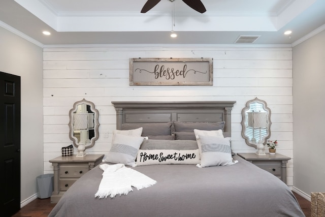 bedroom with a tray ceiling, ceiling fan, ornamental molding, and dark wood-type flooring