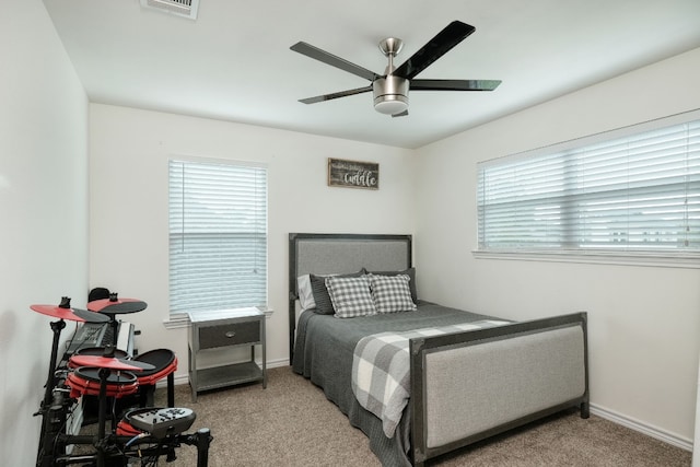 bedroom with light colored carpet, ceiling fan, and multiple windows