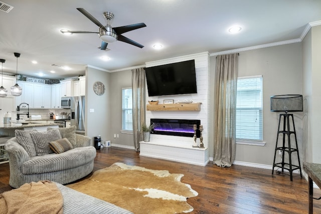 living room with dark hardwood / wood-style flooring, a wealth of natural light, a fireplace, and ceiling fan with notable chandelier