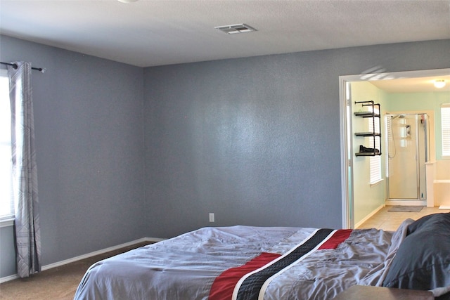 bedroom with a textured ceiling, light colored carpet, and multiple windows