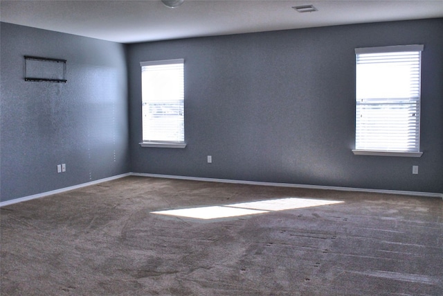 empty room featuring dark carpet and a healthy amount of sunlight