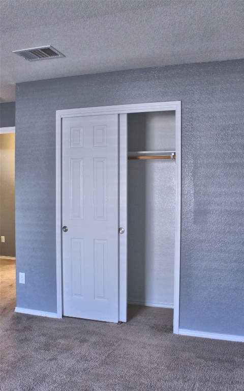 exterior space with a closet, dark colored carpet, and a textured ceiling